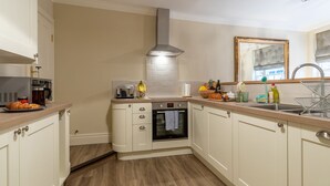 A kitchen with white cabinets, a built-in oven, a stainless steel range hood, and a wooden countertop. - Apt 2, 71 Micklegate, YORK (York)