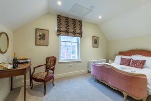 Une chambre à coucher avec un lit, une chaise, un bureau, une fenêtre et un radiateur.