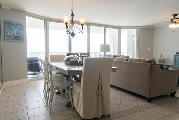 A spacious living room with a large sofa, a dining table, and a chandelier.
