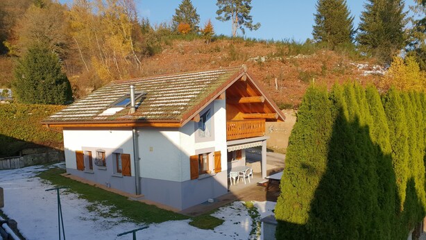 Une maison à deux étages, dotée d’un toit en pente, d’une façade en bois et d’un balcon.