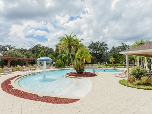 A pool area with a circular design, palm trees, lounge chairs, and a gazebo.