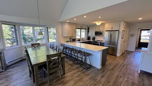 A spacious kitchen with a large island, wooden flooring, and ample natural light from large windows.