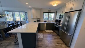 A modern kitchen with a large island, stainless steel appliances, and ample natural light from windows.