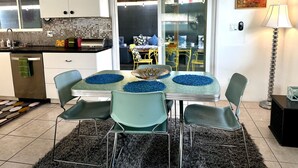 Una cocina moderna con armarios blancos, salpicadero de azulejos y un comedor con mesa y sillas.