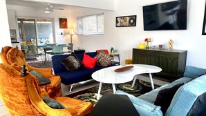 Una sala de estar con sofá, sillones, una mesa de centro y televisor.