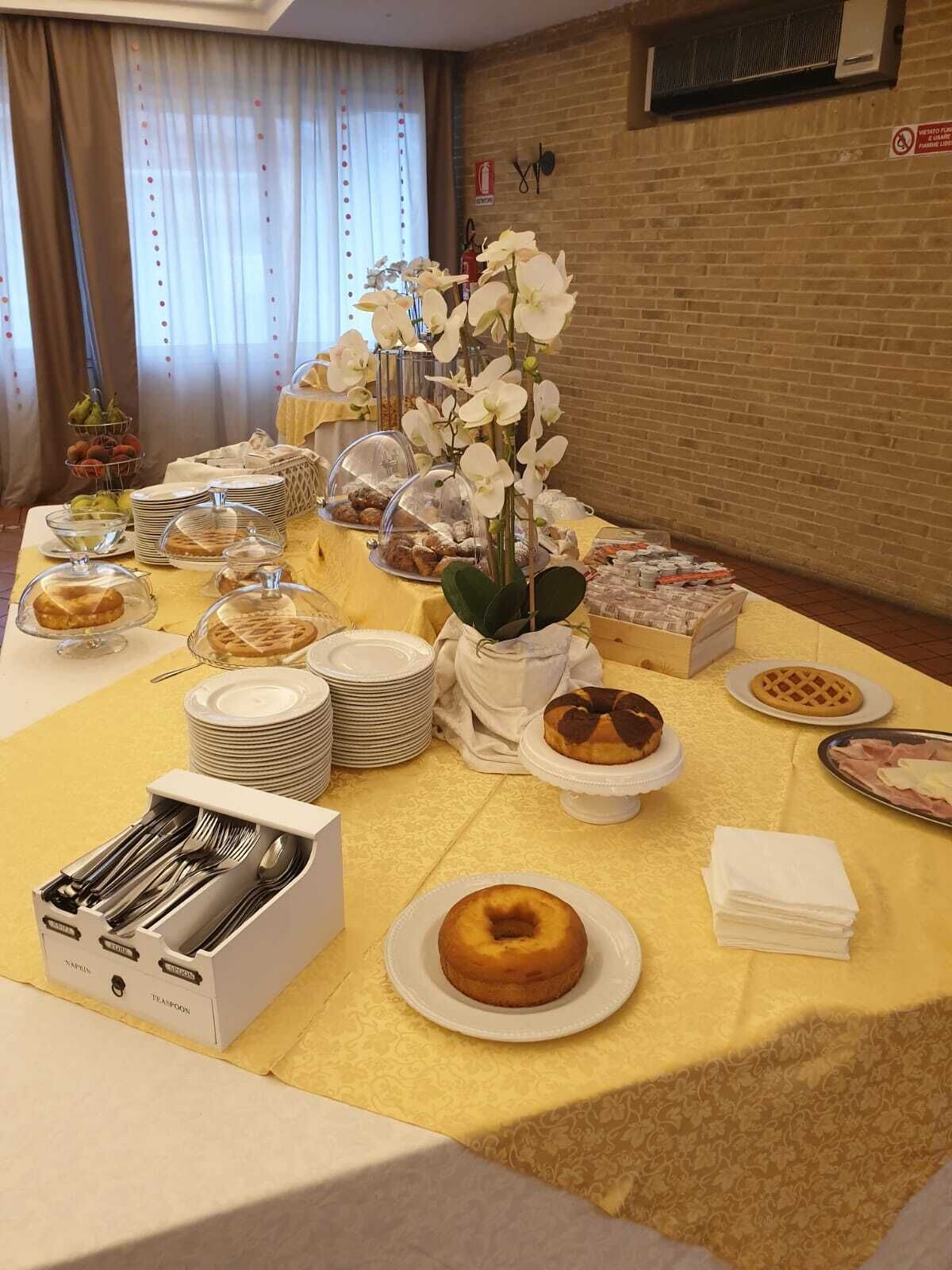Una mesa de buffet con diferentes tipos de comida, incluyendo pasteles y frutas, en un ambiente de hotel.