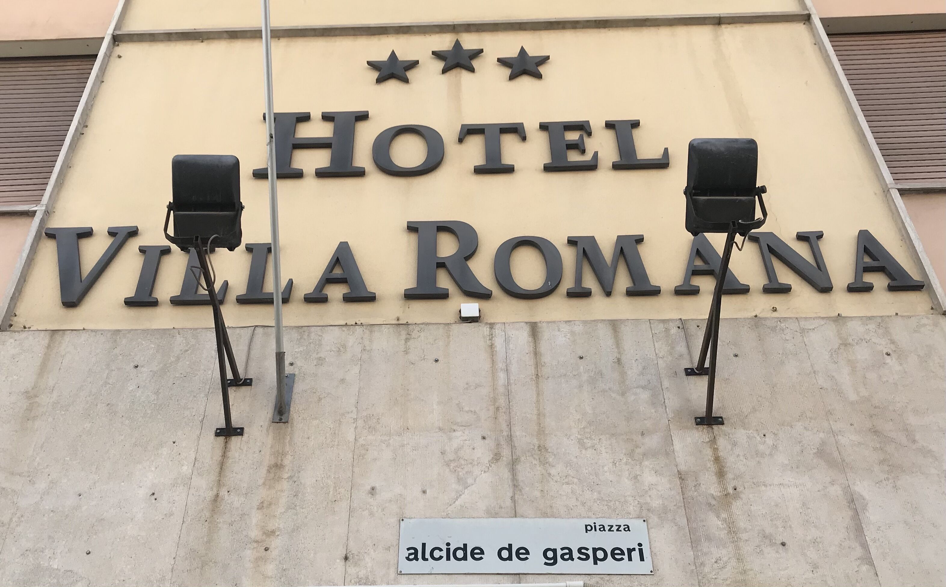 Señal del Hotel Villa Romana con dos altavoces montados en postes.