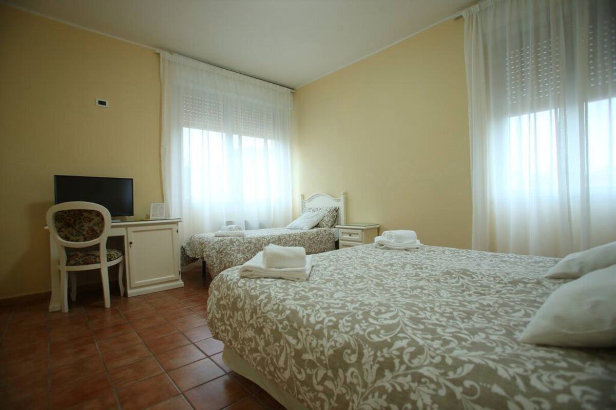 Une chambre d’hôtel avec deux lits, un bureau, une chaise et un téléviseur.