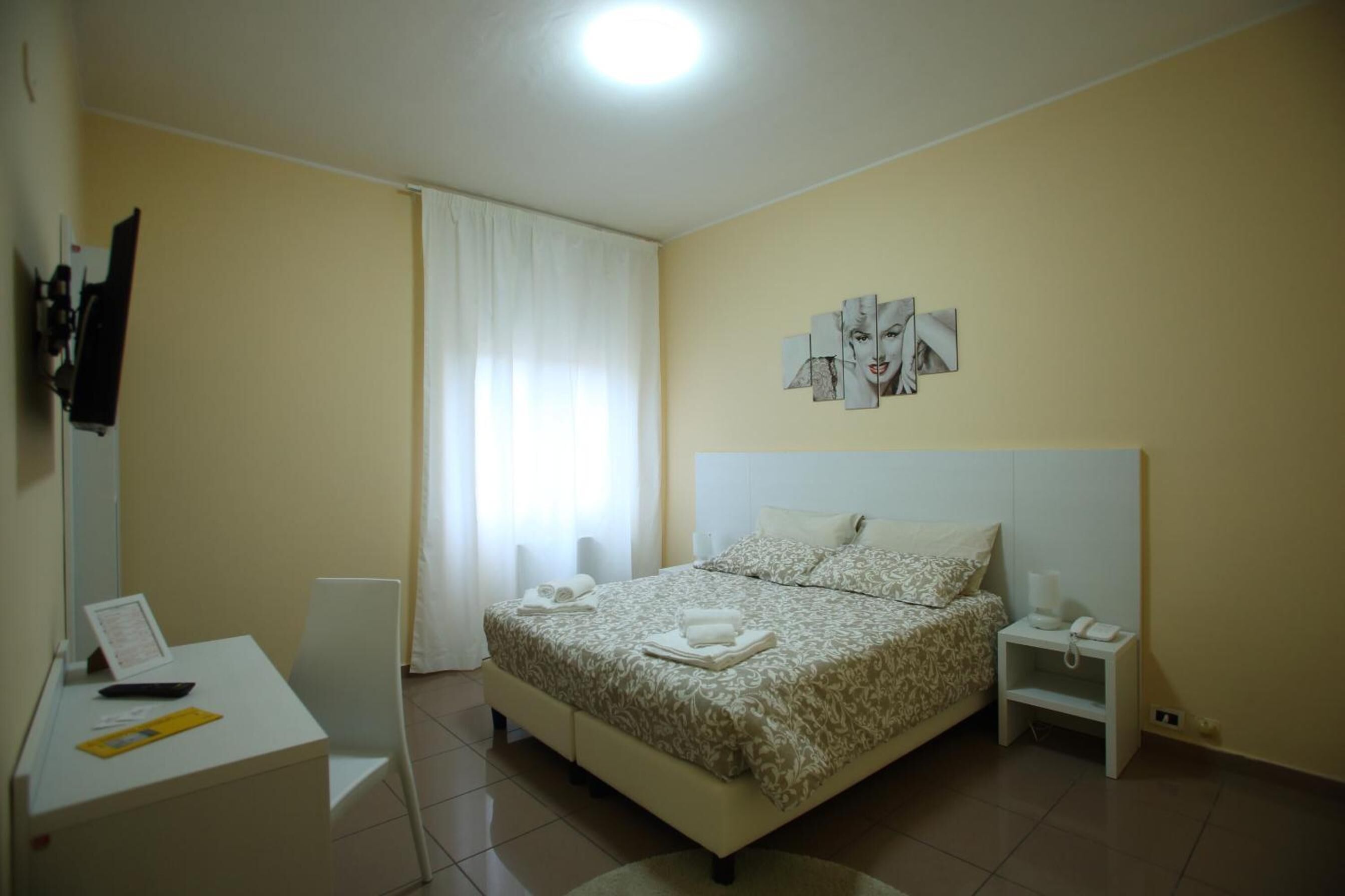 Un dormitorio con cama, mesita de noche y escritorio con silla.