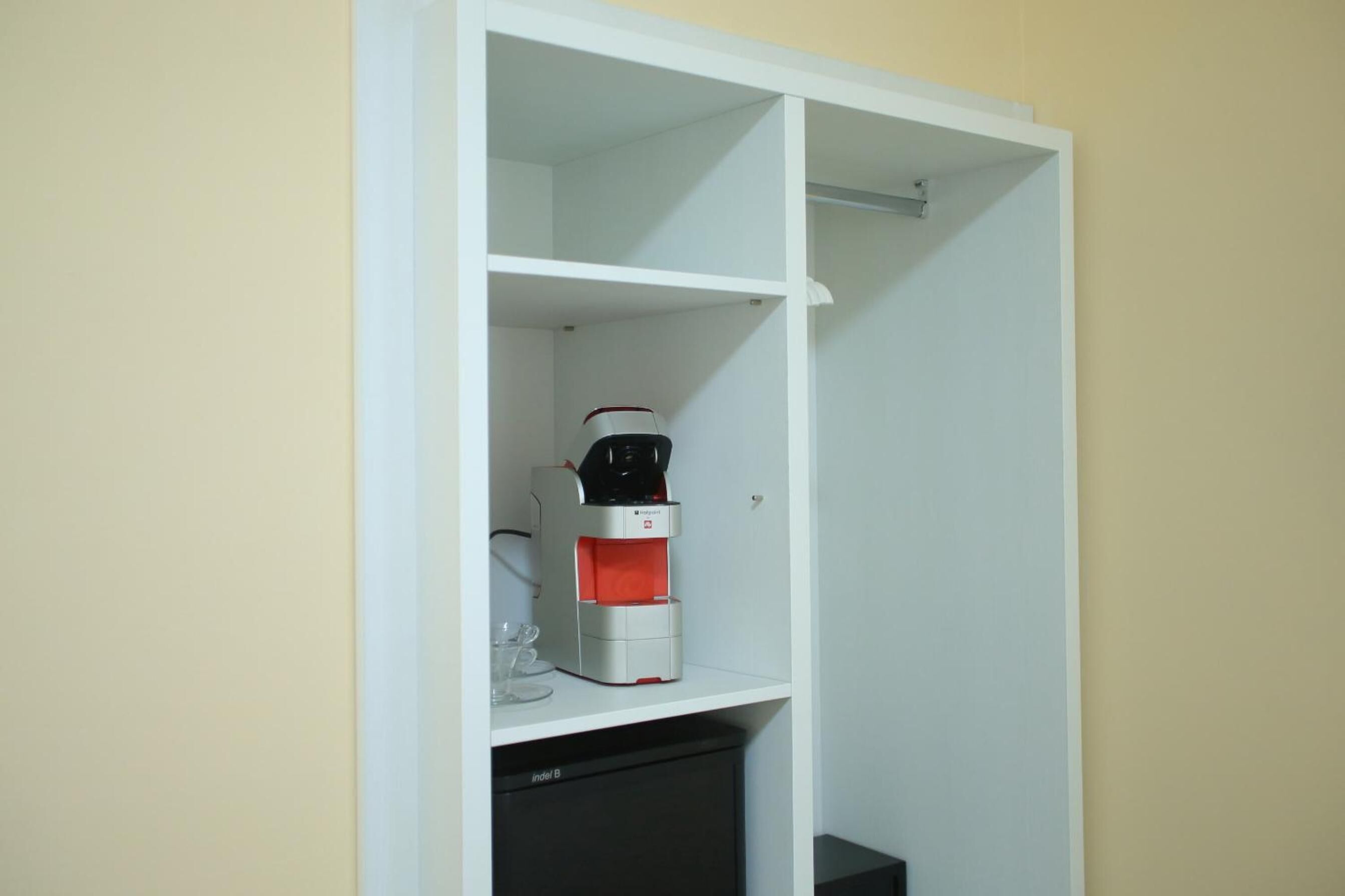 A white shelving unit with a coffee maker and a small refrigerator.