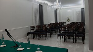 A conference room with rows of chairs, a microphone, and a table with plates and glasses. - Hotel Villa Romana (Piazza Armerina)