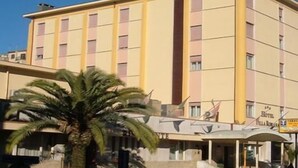 A multi-story hotel with a yellow facade, a prominent vertical column, and a sign indicating it is a hotel. - Hotel Villa Romana (Piazza Armerina)