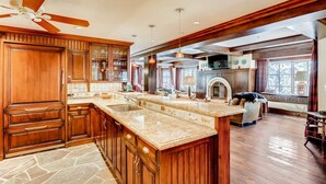 A spacious kitchen with wooden cabinets, a large island, and a fireplace. - 1-#28 One Willow Bridge 3BD (Vail)