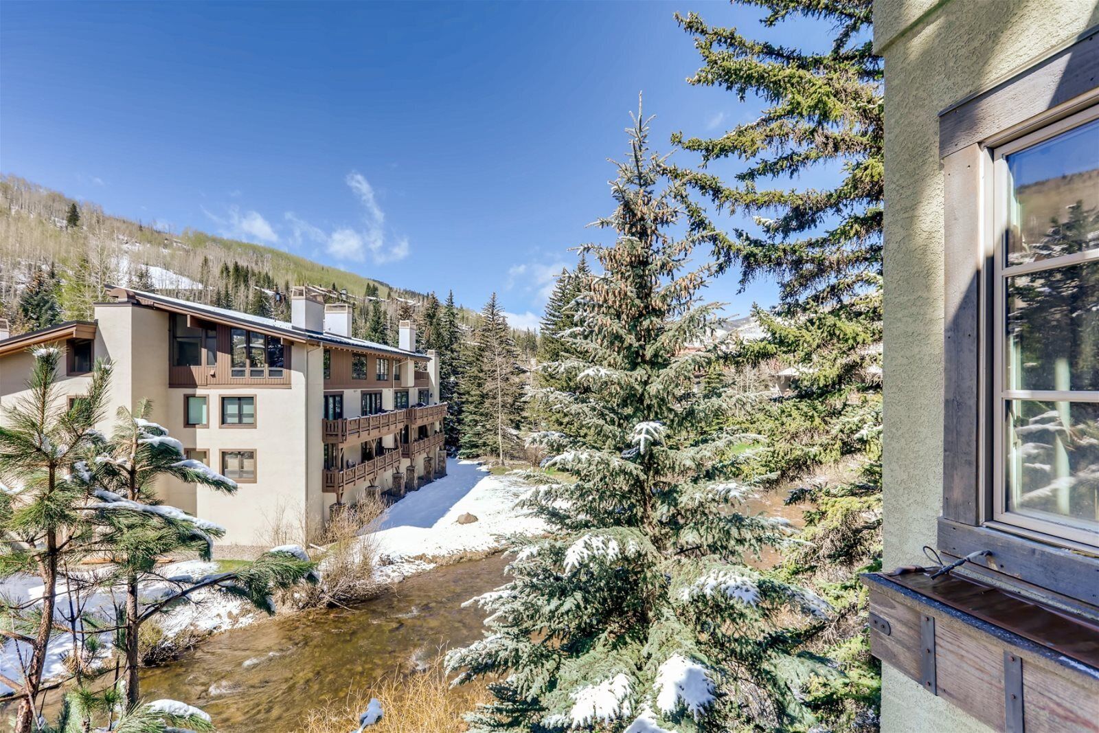 Un edificio de varios pisos con balcones, un paisaje cubierto de nieve y un río.