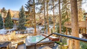 A hot tub in a forested area with a wooden deck and stone steps leading to it. - 1-184 West Meadow Drive (Vail)