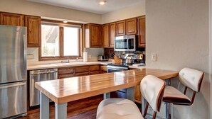 Una cocina moderna con armarios de madera, electrodomésticos de acero inoxidable y una isla central con asientos.