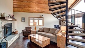 Una sala de estar acogedora con chimenea, un sofá, una mesa de centro y una escalera en espiral.