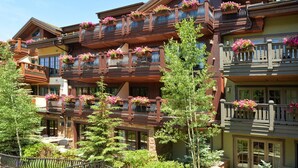 Un hotel de varios pisos con balcones decorados con jardineras, paredes de piedra y fachada de madera.