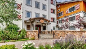 Ein Hotel mit einer Stein-Fassade, einem hölzernen Eingang und einem gepflegten Garten mit verschiedenen Pflanzen und Blumen.