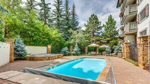 Ein rechteckiger Pool mit Steinumrandung, umgeben von einer Pflasterterrasse.