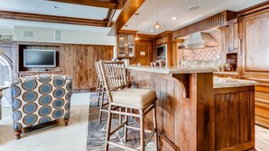 A spacious kitchen with wooden cabinetry, a bar area, and a television in the background. - Vail VLG One Willow 3bd-hag (Vail)