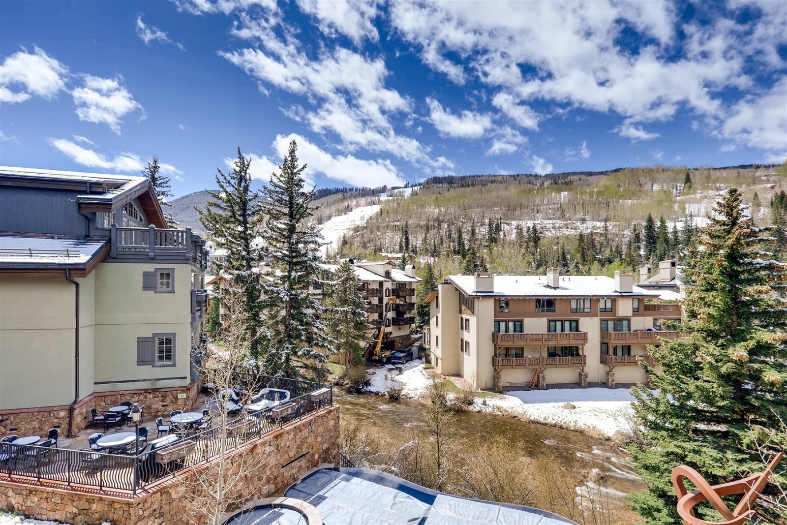 A ski resort with multi-story buildings, outdoor seating, and a view of a snowy mountain.