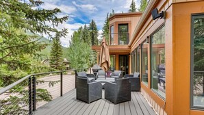 A deck with outdoor furniture, a covered seating area, and a view of a mountainous landscape.