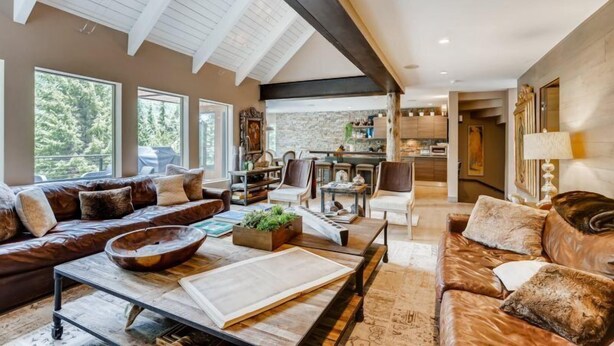 A spacious living room with a high ceiling, large windows, a fireplace, and a cozy seating area.