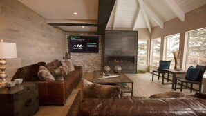 A modern living room with a fireplace, leather furniture, and a TV mounted on the wall.