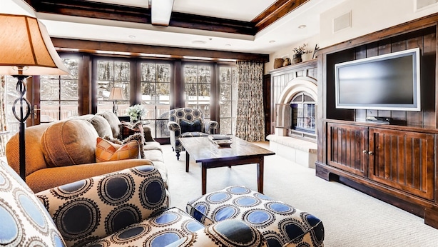 A spacious living room with a fireplace, a television, and large windows offering a view of the outdoors. - Vail VLG One Willow 3bd-win1 (Vail)