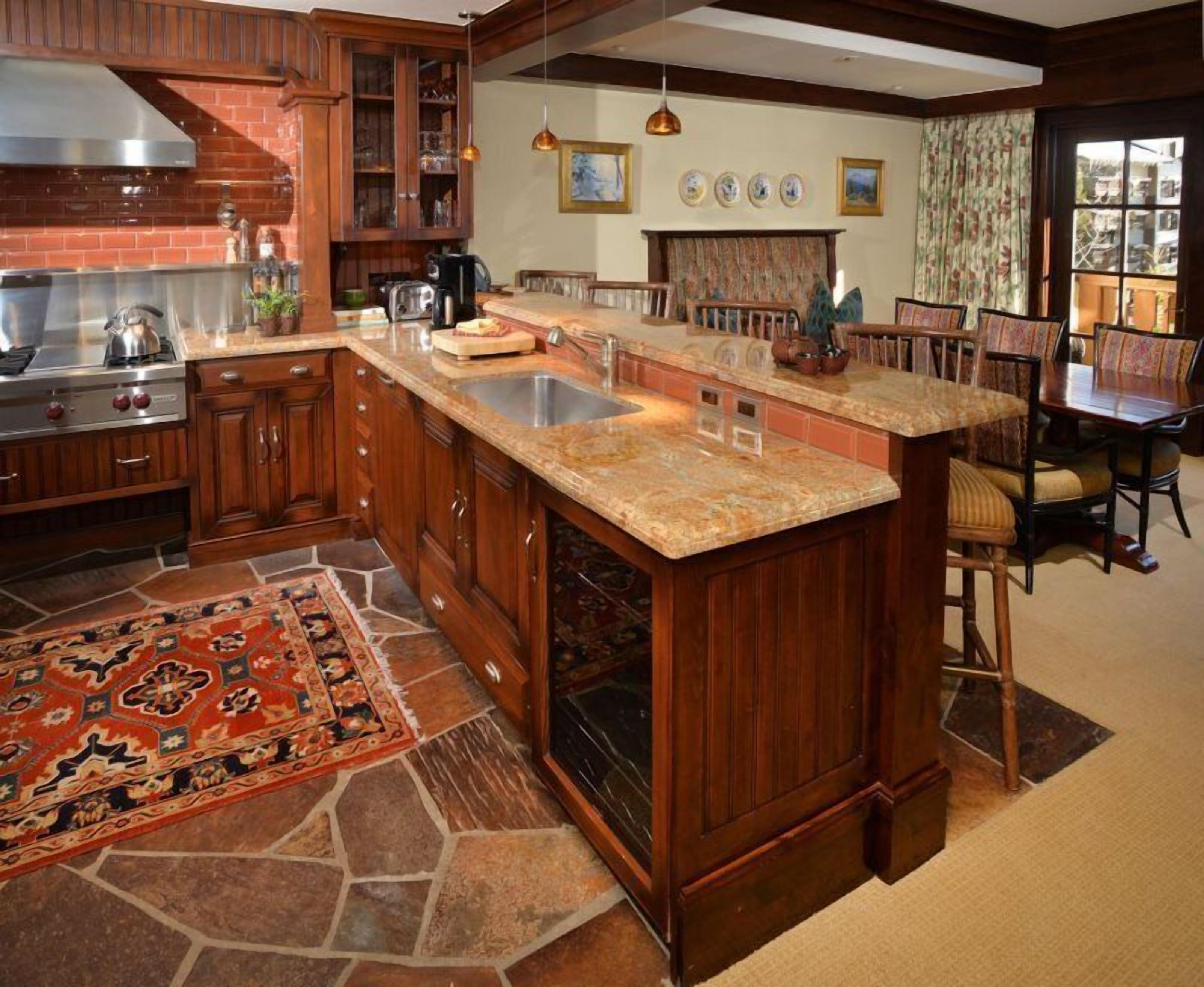 A kitchen with wooden cabinets, a granite countertop, a built-in oven, and a large island with a sink.
