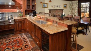 A kitchen with wooden cabinets, a granite countertop, a built-in oven, and a large island with a sink. - Vail VLG One Willow 2bd-joh1 (Vail)