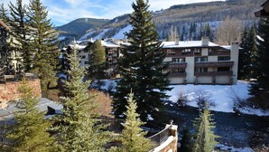 A mountain resort with multiple buildings, a ski slope in the background, and a river in the foreground. - Vail VLG One Willow 2bd-joh1 (Vail)