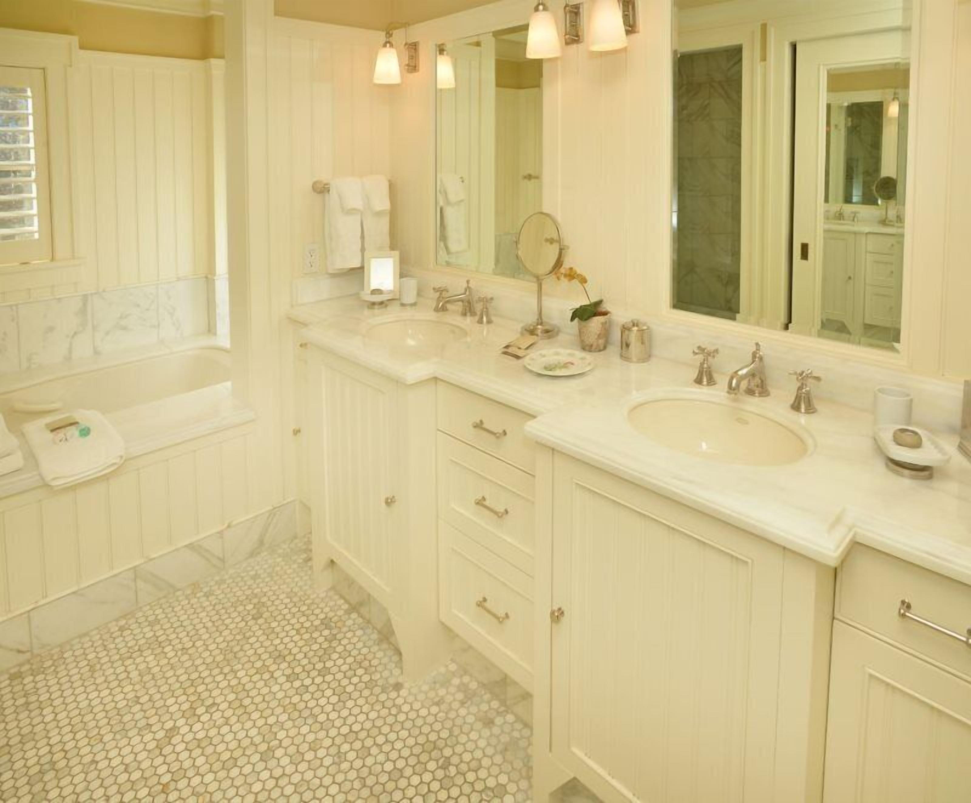 A bathroom with two sinks, a bathtub, and a large mirror.