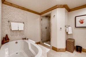 A modern bathroom with a freestanding bathtub, a glass-enclosed shower, and a wooden ceiling.