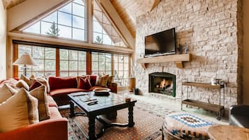 Un salón amplio con chimenea, ventanas grandes y una pared de piedra.