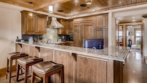 Une cuisine spacieuse avec des meubles en bois, un plan de travail en marbre et un grand îlot central doté de tabourets de bar.