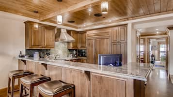 Una cocina amplia con armarios de madera, encimera de mármol y una isla grande con taburetes de bar.