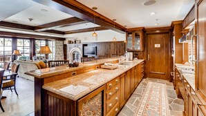 A spacious kitchen with a long island, wooden cabinets, and a stone backsplash.