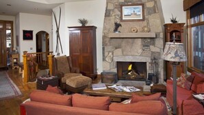 Ein gemütliches Wohnzimmer mit Kamin aus Stein, einem roten Sofa und einem Holztisch.