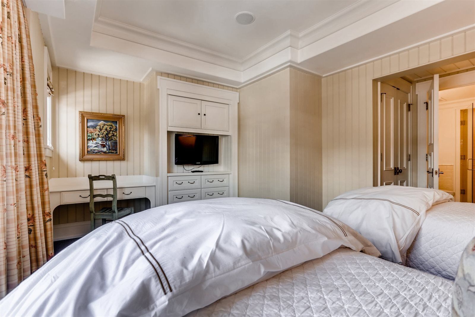 A hotel room with a bed, a desk with a television, and a wardrobe.
