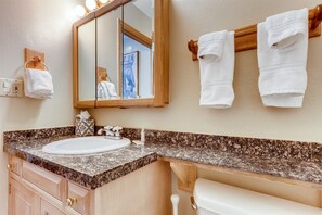 A bathroom with a granite countertop, a sink, a mirror, and two towels hanging on a wooden towel rack. - 1-scorpio 403 (Vail)