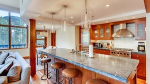A modern kitchen with a large island, stainless steel appliances, and wooden cabinets. - 1-385 Gore Creek Dr. Vorlaufer #303 (Vail)
