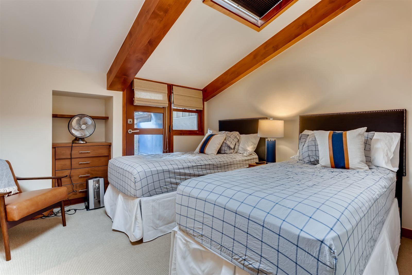 A bedroom with two beds, a wooden dresser, a desk, and a chair.
