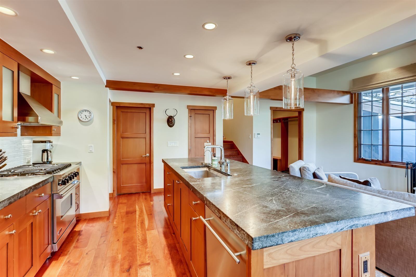 Una cocina con armarios de madera, una isla grande, una estufa y luces colgantes.