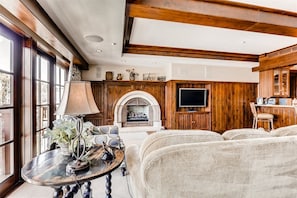 Ein gemütliches Wohnzimmer mit Kamin, Fernseher und Essbereich mit Holzwandverkleidung.