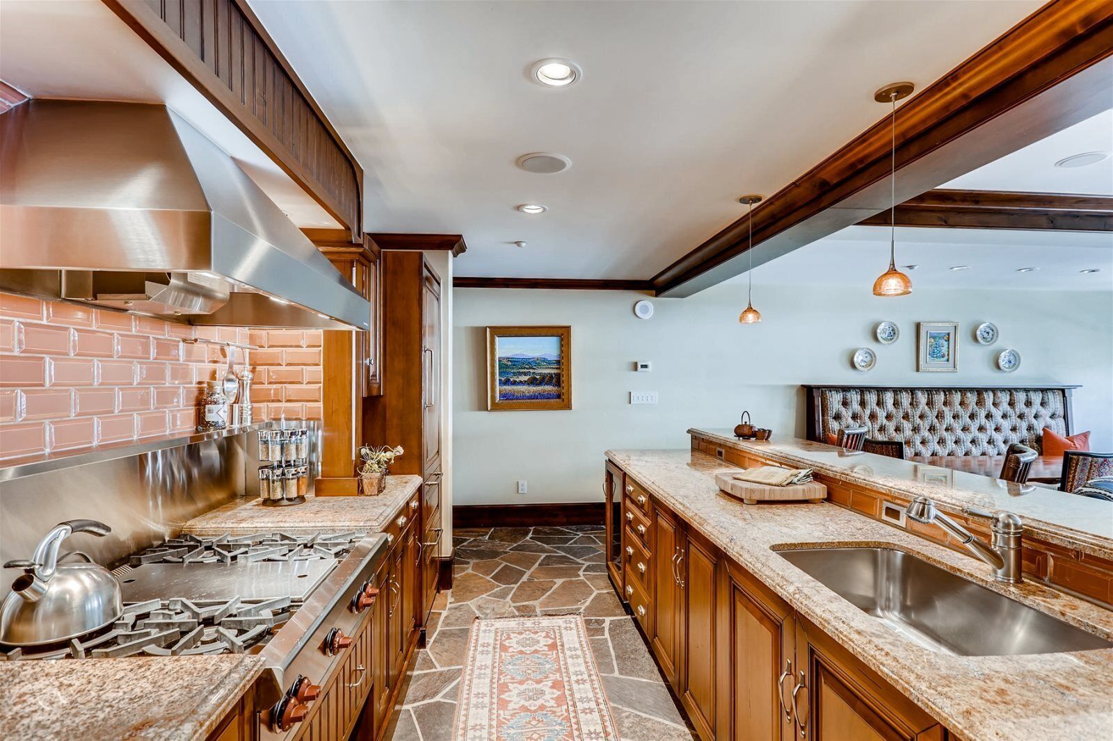 A modern kitchen with granite countertops, stainless steel appliances, and a stone backsplash.