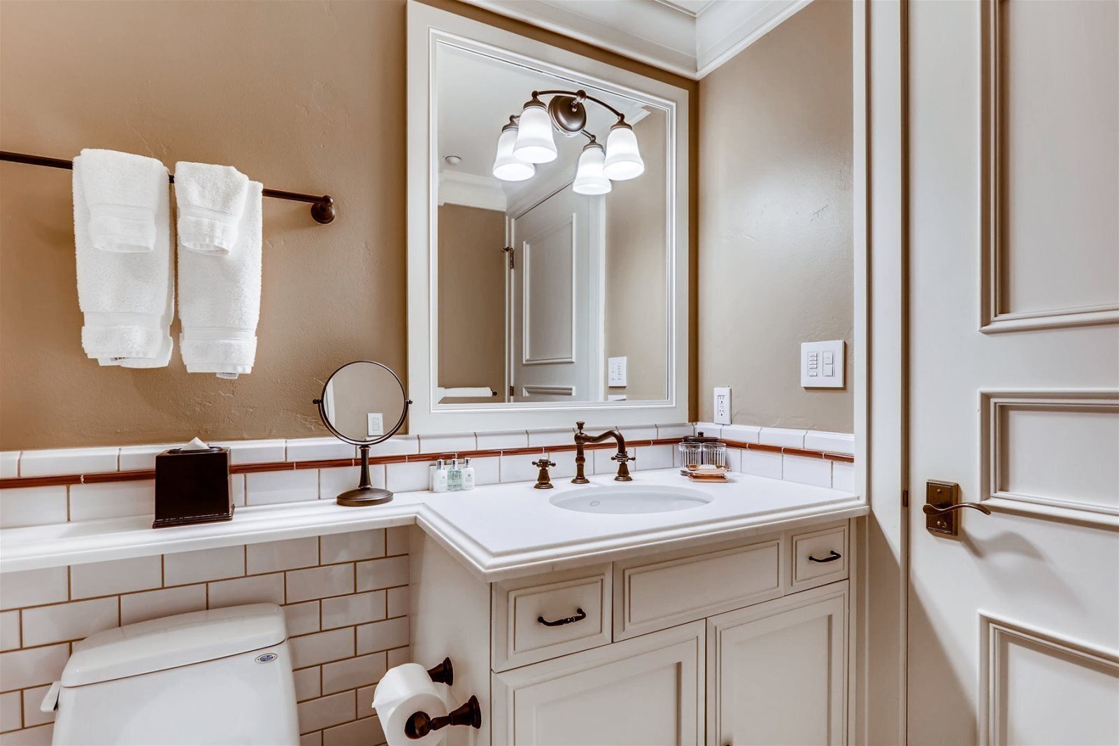 A bathroom with a white sink, a mirror, and two towels hanging on the wall.
