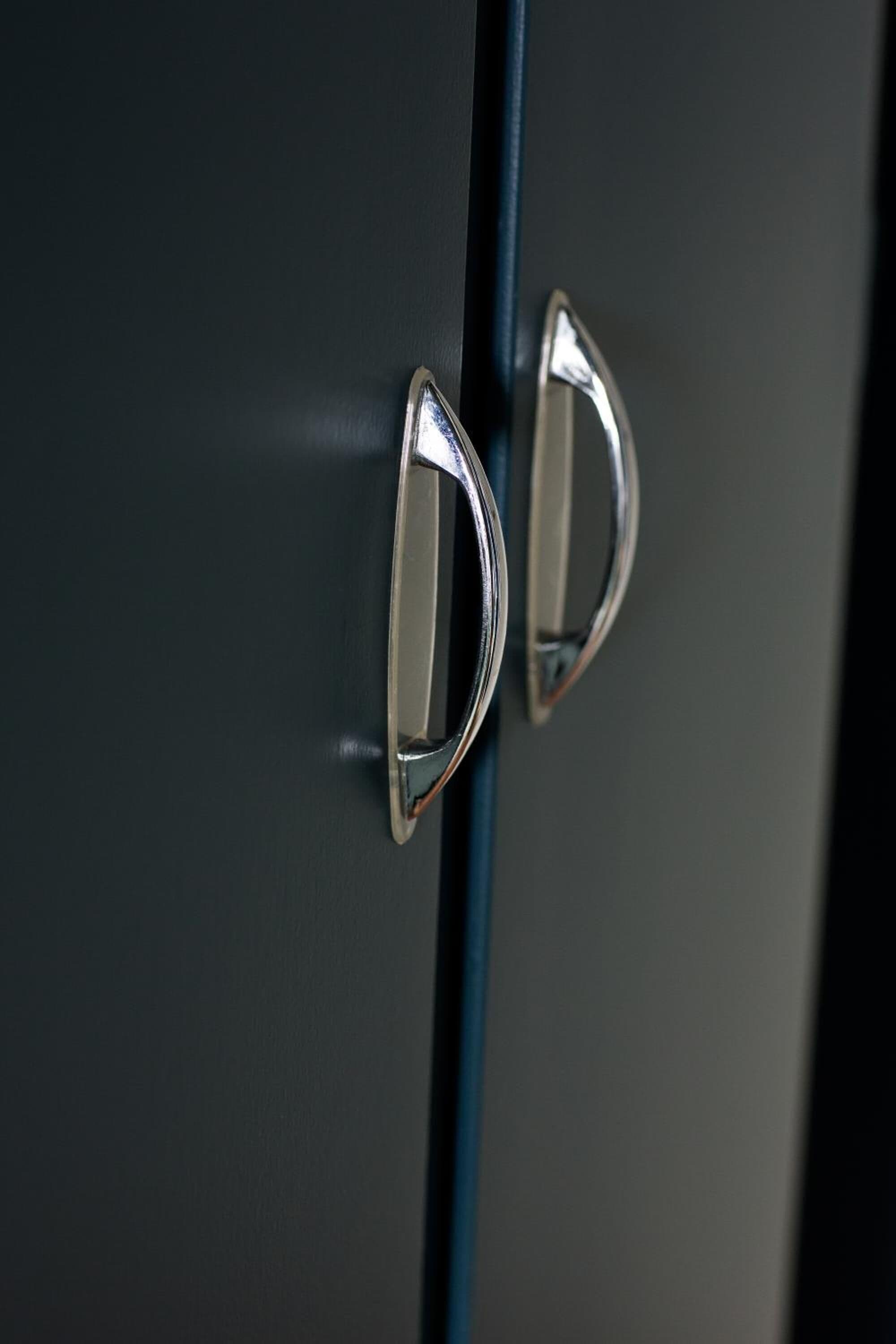 A close-up of a metallic handle on a dark-colored door.