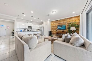 A modern living room with a sofa set, a coffee table, and a kitchen area in the background.